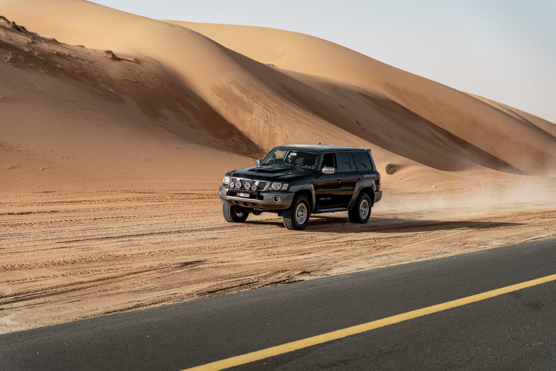 A vehicle beside the sweeping dunes at Liwa Festival